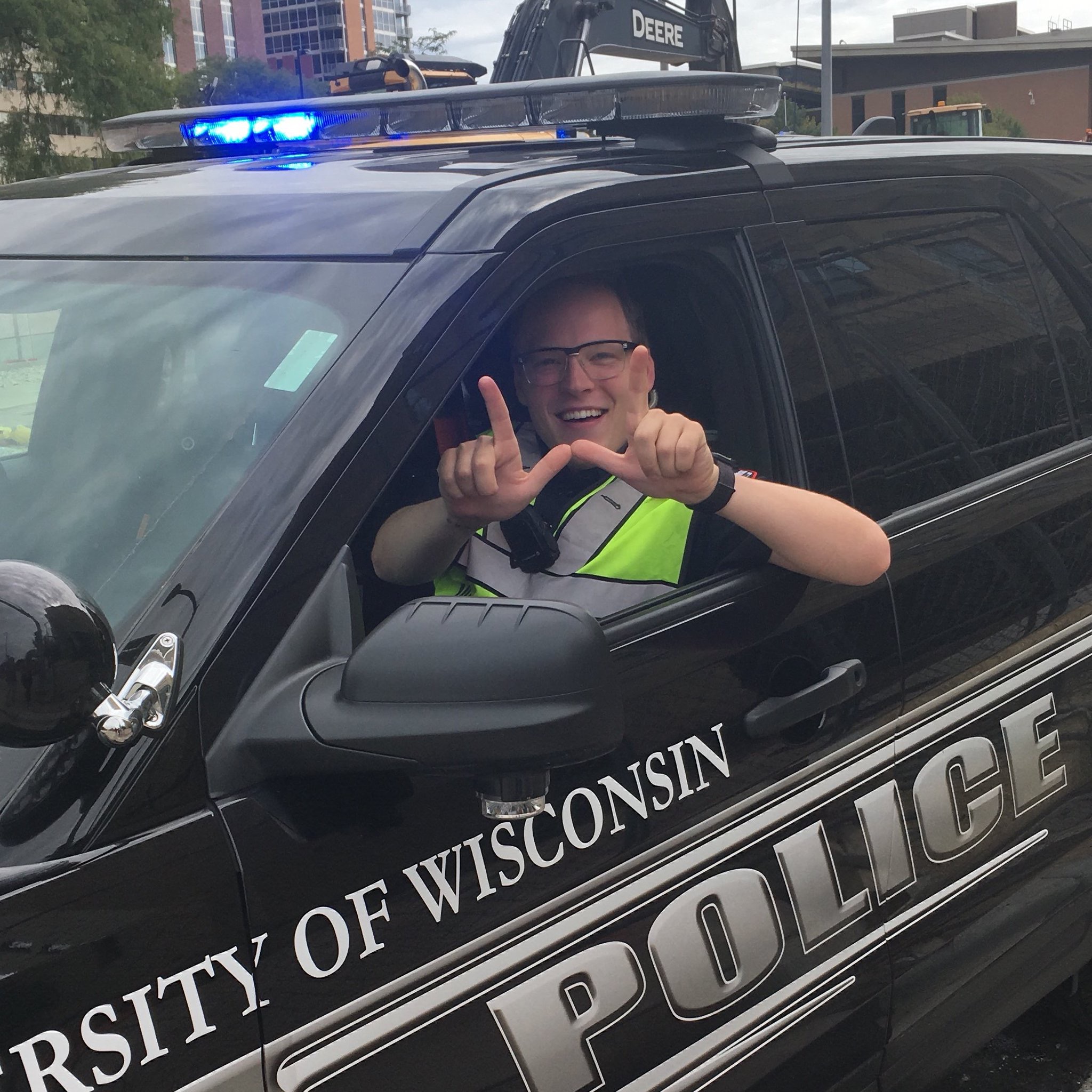 A photo of Officer Jake Lepper sitting in a police squad car and making a 
