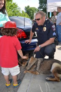 A child pets a dog from the K9 unit, his handler nearby.