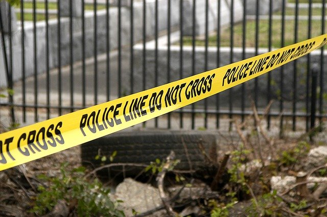 Yellow tape reading 'Police Line Do Not Cross' surrounds a scene.