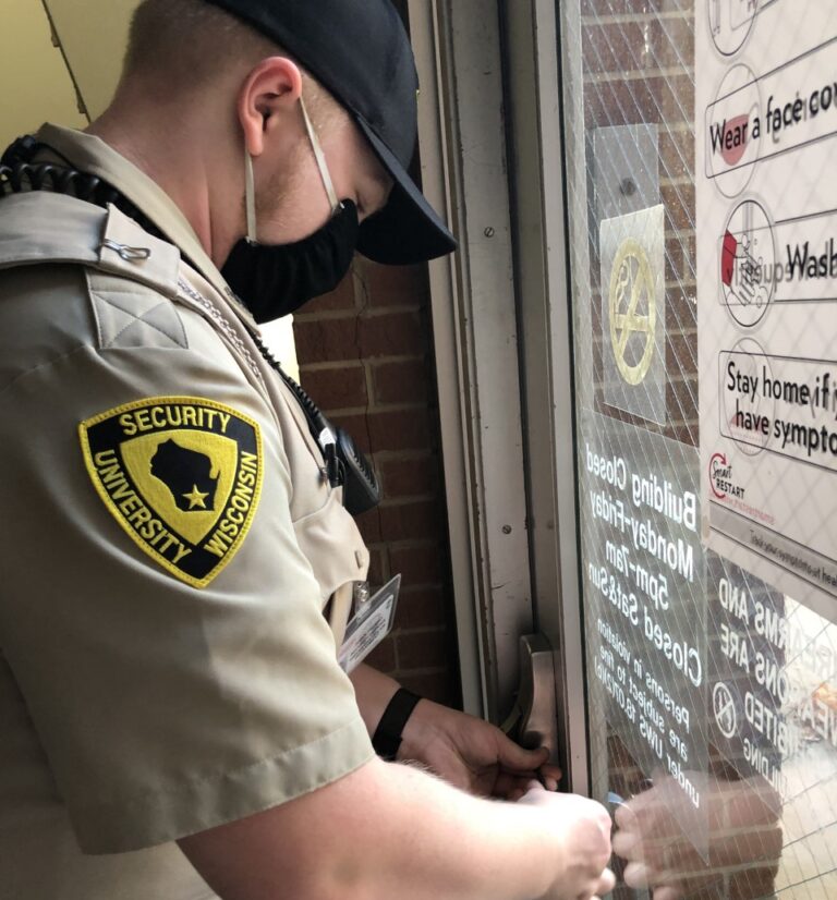 A security guard locks a building door.